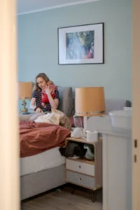 Ein Foto von einem Babyshooting. Zu sehen ist eine Mutter und Baby in einer Alltagssituation. Sie macht ihr Baby gerade fertig zum Stillen.